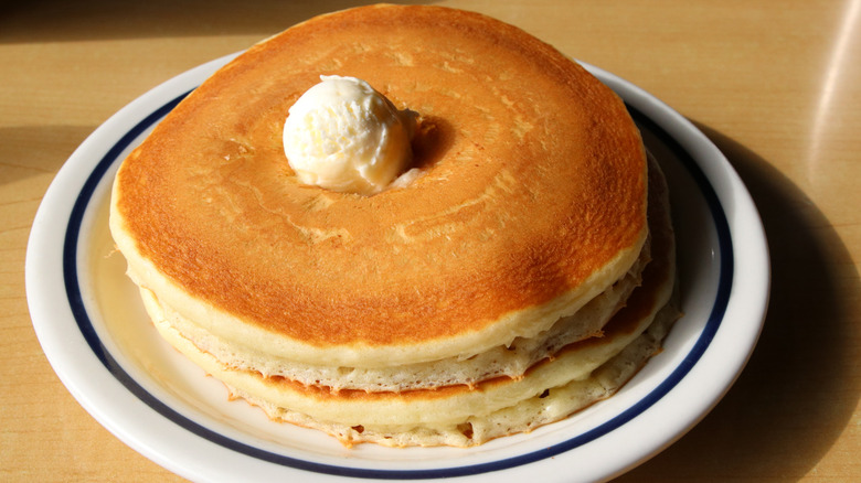 A stack of three pancakes topped with unmelted butter