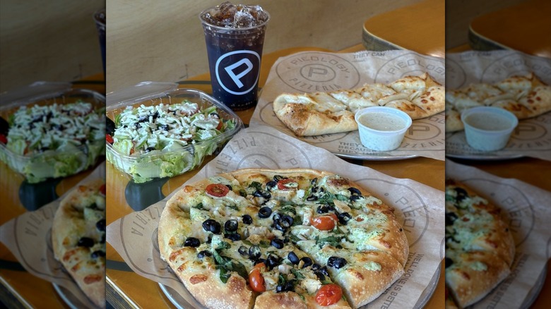 Pieology pizza, salad, cheesy bread, and drink on table
