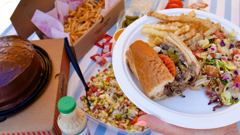 Portillo's sandwich, fries, salad, and chocolate cake on picnic table