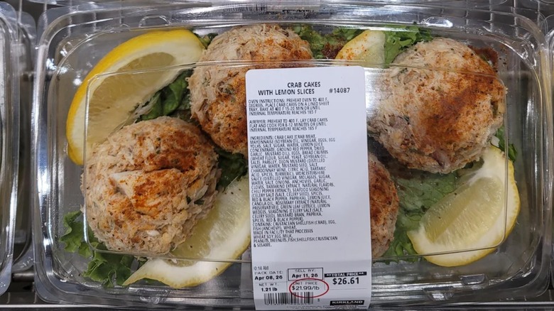 A plastic package of Costco's fresh crab cakes with lemon wedges and leaf lettuce