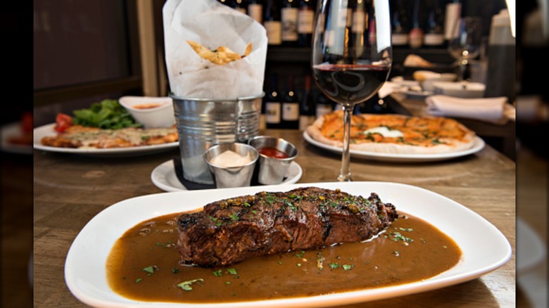 New York strip steak au poivre with side of fries and glass of wine