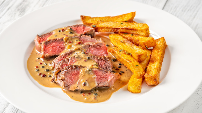Sliced steak au poivre, medium rare, with a peppercorn sauce and french fries