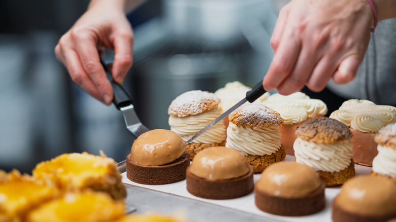 A baker putting together a baked pastry in a display case.
