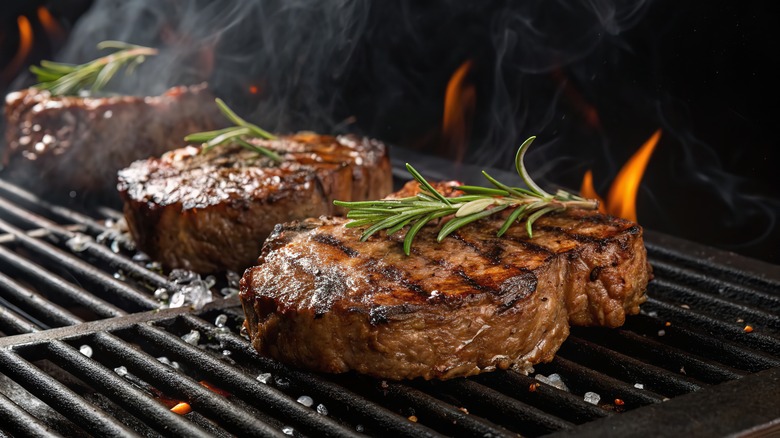 Flame-grilling steaks topped with rosemary