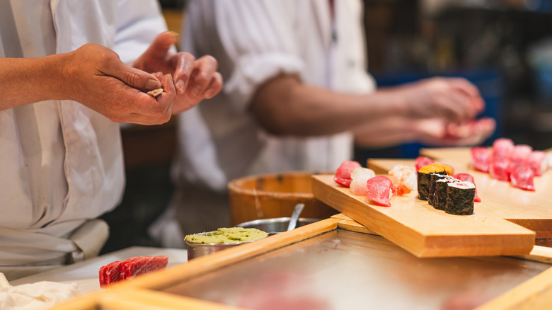 Sushi chefs preparing fresh sushi rolls