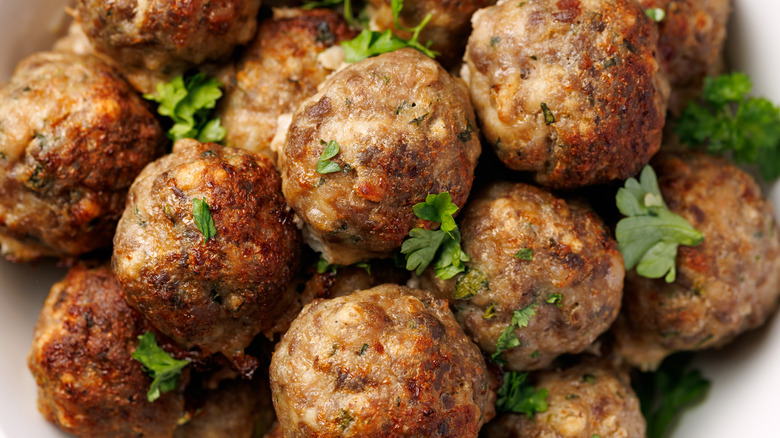 Closeup of meatballs in a dish garnished with fresh parsley