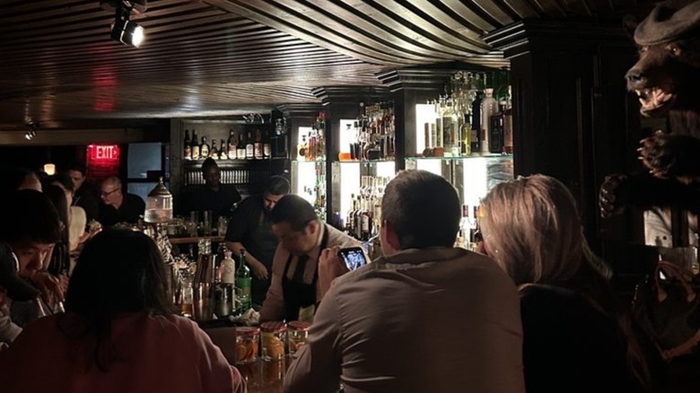 The interior of Please Don't Tell, a speakeasy in the Manhattan, with several patrons inside