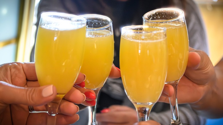 Hands cheersing four Mimosas