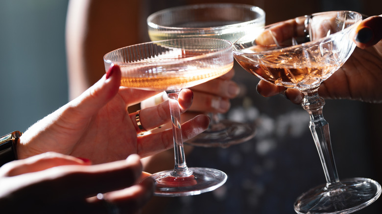 Several people clinking martini glasses together in a toast