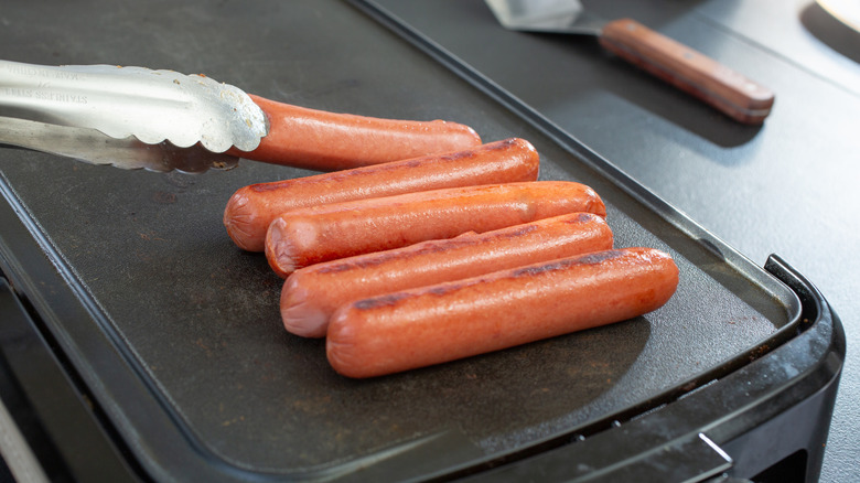 Hot dogs being cooked on a griddle