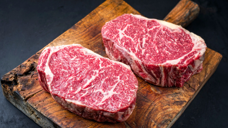 two aged Wagyu steaks with lots of marbling on a rustic cutting board