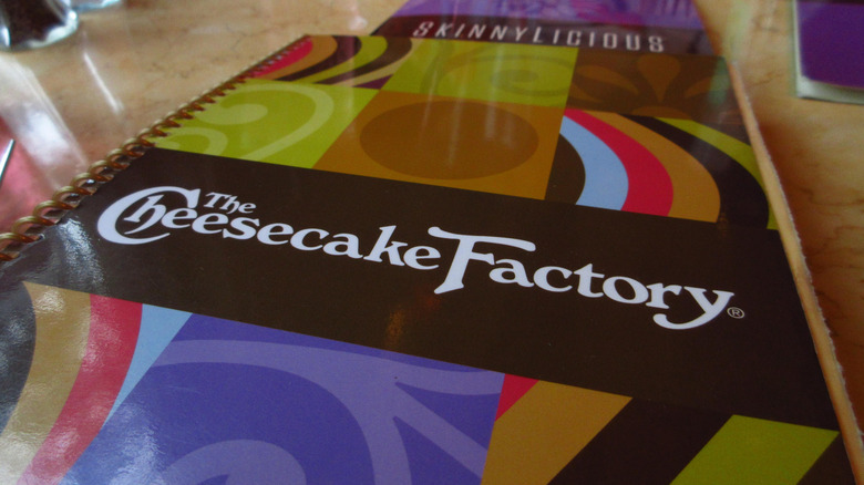 A Cheesecake Factory menu is closed on top of a table.