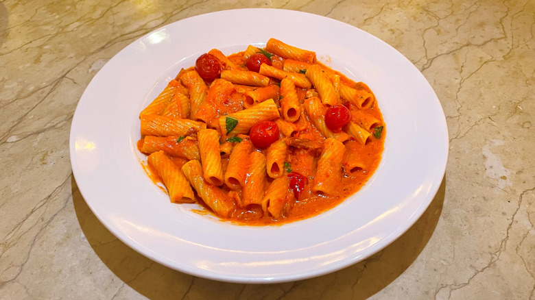 A bowl of spicy rigatoni pasta from The Cheesecake Factory is on a table.