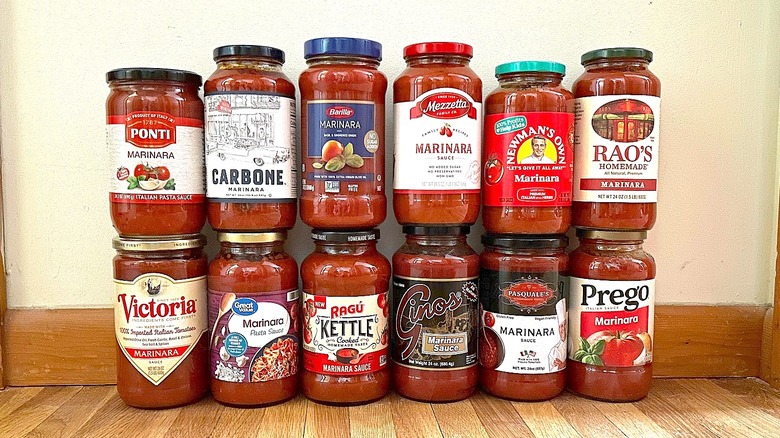 Twelve jarred marinara sauces stacked in front of a plain wall