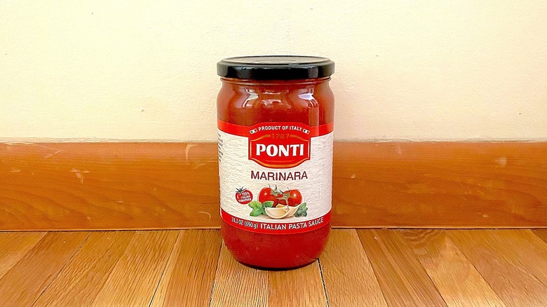 A jar of Ponti marinara sauce in front of a plain wall