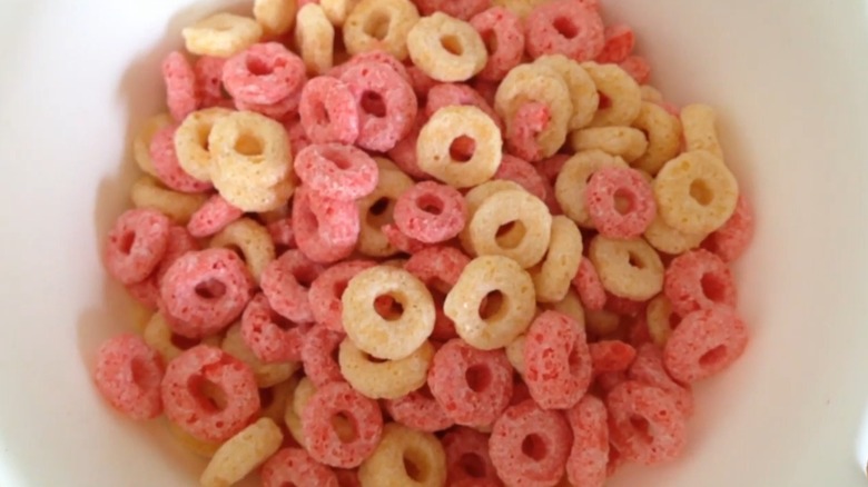 A white bowl of yellow and pinkish-red cereal loops