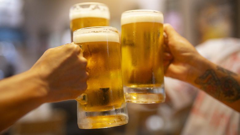 Hands holding mugs of beer in toast