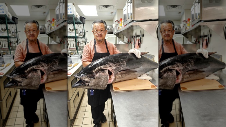 Chef Michael Chuong holding large fish in restaurant kitchen