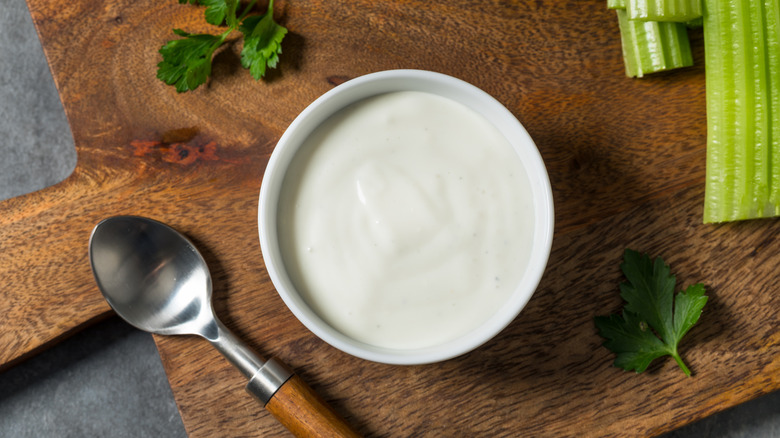 Small bowl of white dressing with parsley, celery, and a spoon