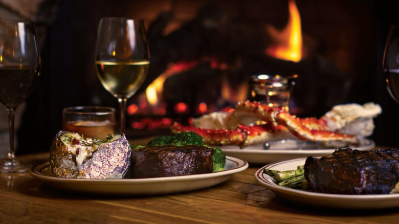 A table set with surf and turf dinner sits in front of a fire at The Drover