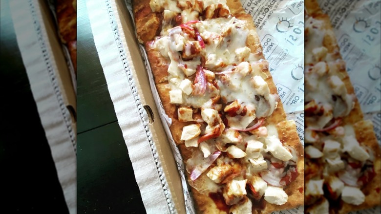 A Cosi flatbread, topped with chicken, cheese, and red onion