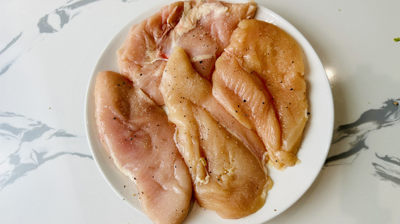 raw chicken breasts on a white plate