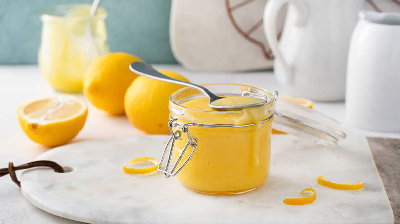 Lemon curd in jar with fresh lemons