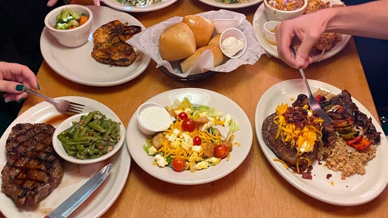 Table with variety of Texas Roadhouse mains and sides