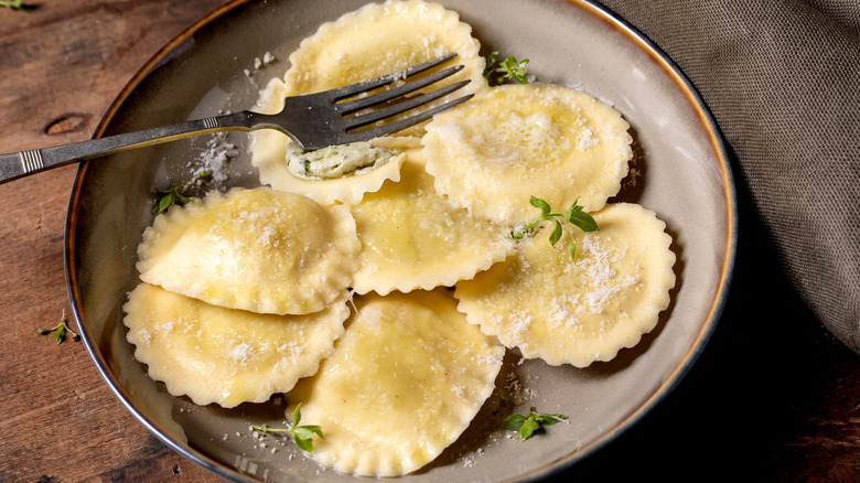ravioli with parmesan and fresh herbs on a plate with a fork