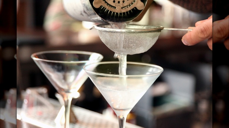 straining martinis into glasses