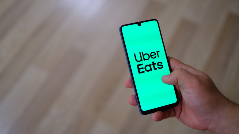 A hand holding a phone with Uber Eats on the screen