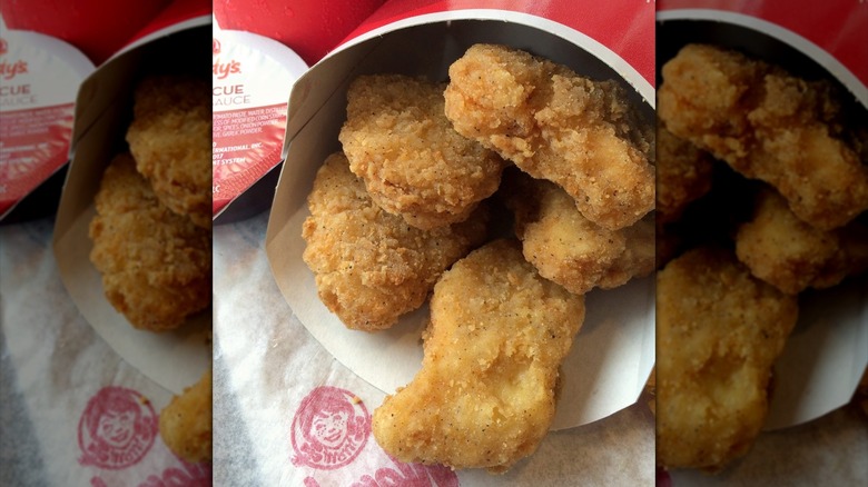 Carton of Wendy's chicken nuggets with cup of barbecue sauce.