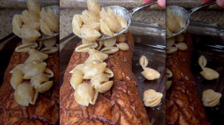 Spoon adding mac and cheese to drunken loaf