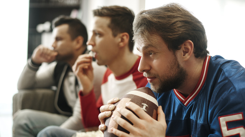 three men watching football