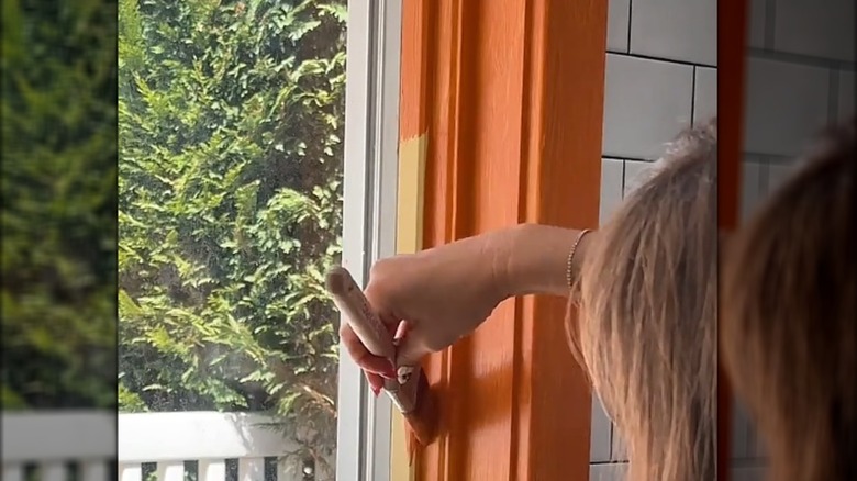 Woman painting window frame in orange paint
