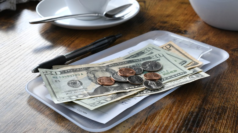 cash and coins sitting on restaurant bill