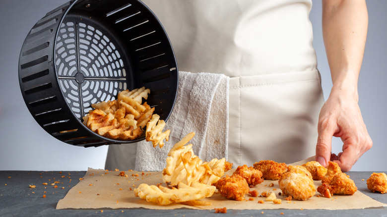 Person dumping fries from air-fryer basket