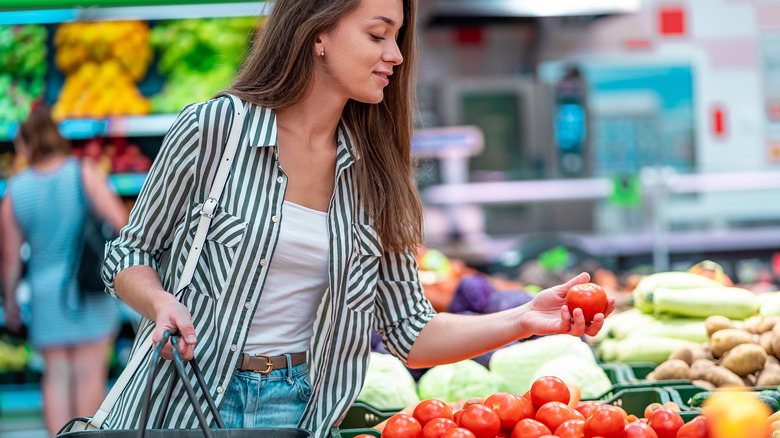 Woman choosing tomatoes in store