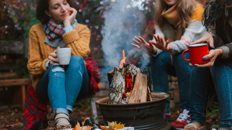 women sitting around campfire with wine