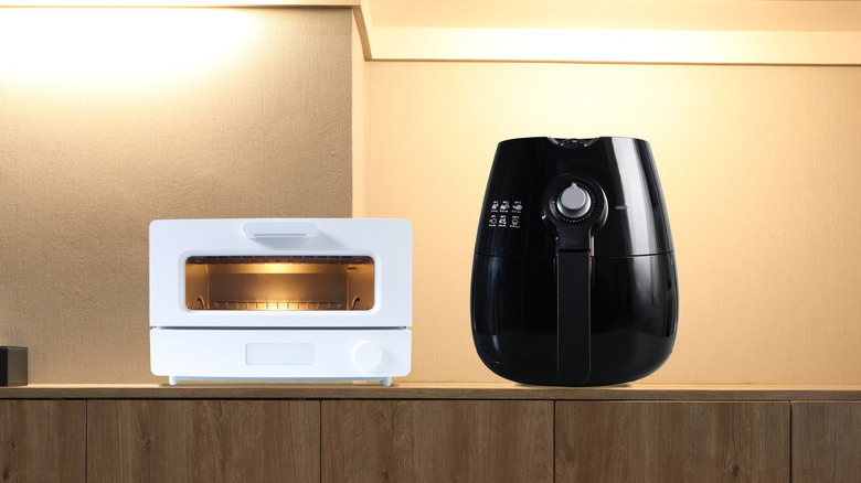 White toaster oven and black air fryer side by side on a counter