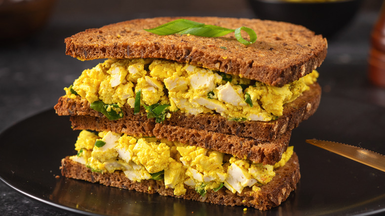 Vegan egg salad sandwich stacked on plate