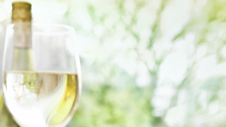 A glass of white wine with the wine bottle in the background