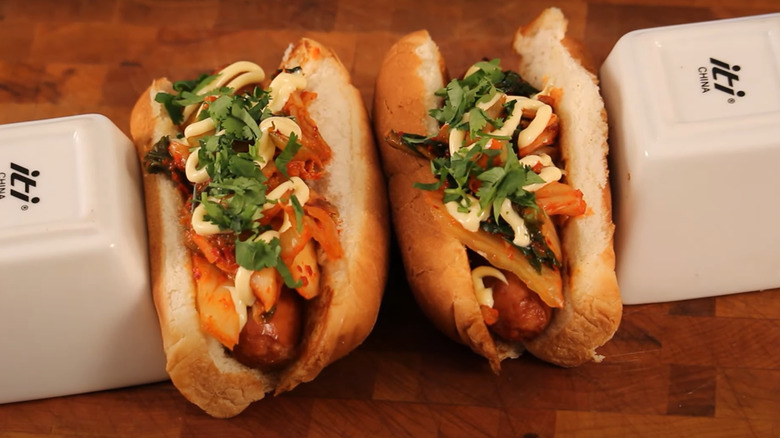 two hot dogs topped with kimchi