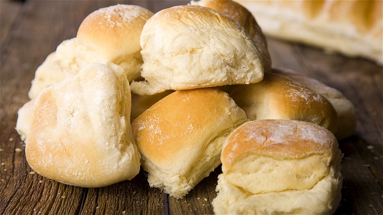 Pile of store-bought dinner rolls on wood board