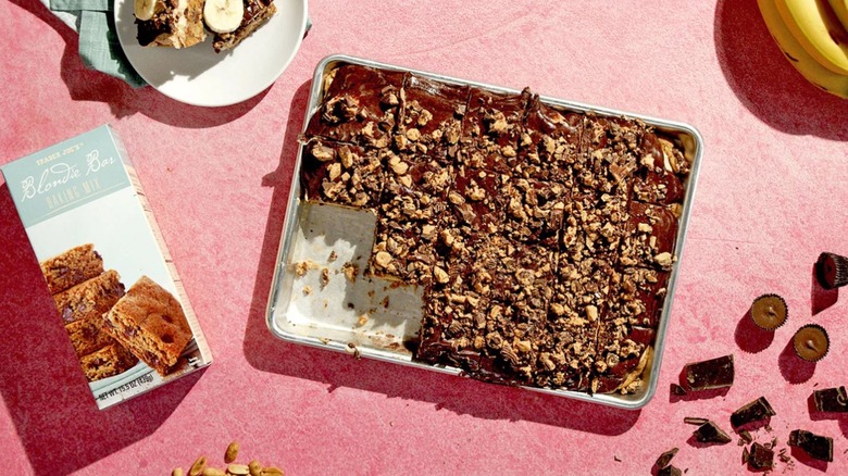 A tray of Blondie Bar Baking Mix next to a box, several ingredients, bananas, against a pink background