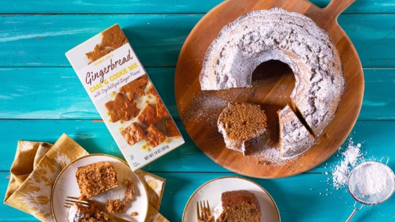 a wood board with Trader Joe's Gingerbread Cake & Cookie Mix next to a package and a plate with a slice of the cake