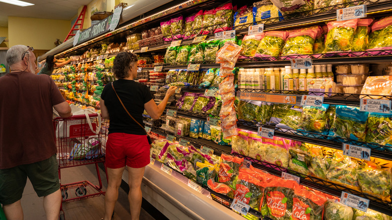 two people browse the bagged salad section of Trader Joe's