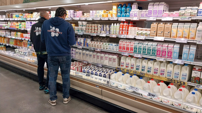 two Trader Joe's employees inspect the milk section