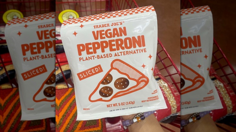 Hand holds Trader Joe's Vegan Pepperoni bag over cart in store