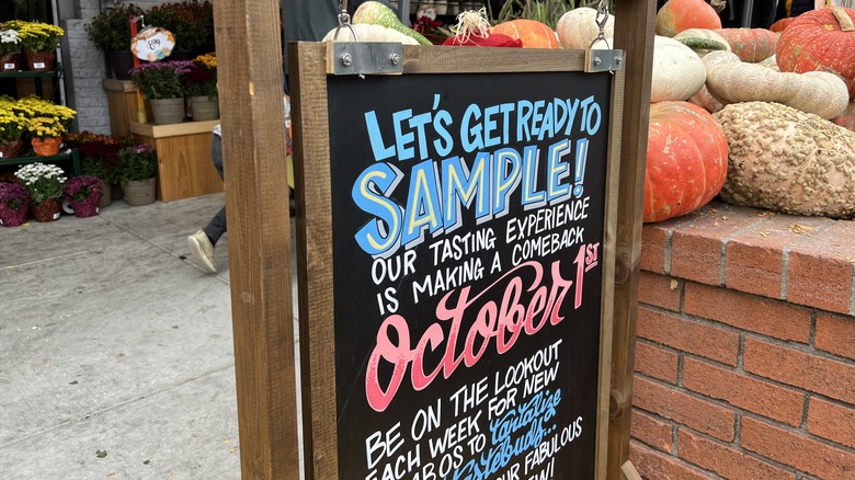 a chalkboard sign outside of Trader Joe's with pumpkins nearby